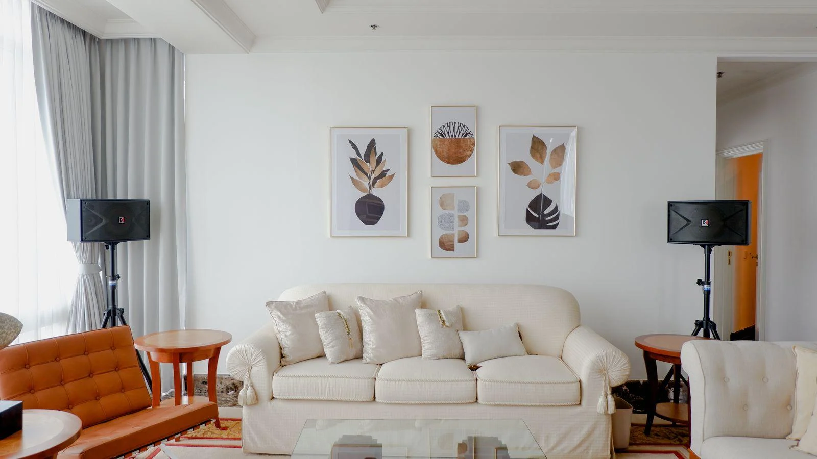 Botanical artworks above a cream sofa in a warm white interior.