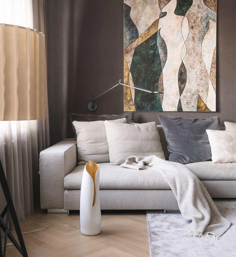 An oversized vertical abstract artwork occupying the wall above a sofa.