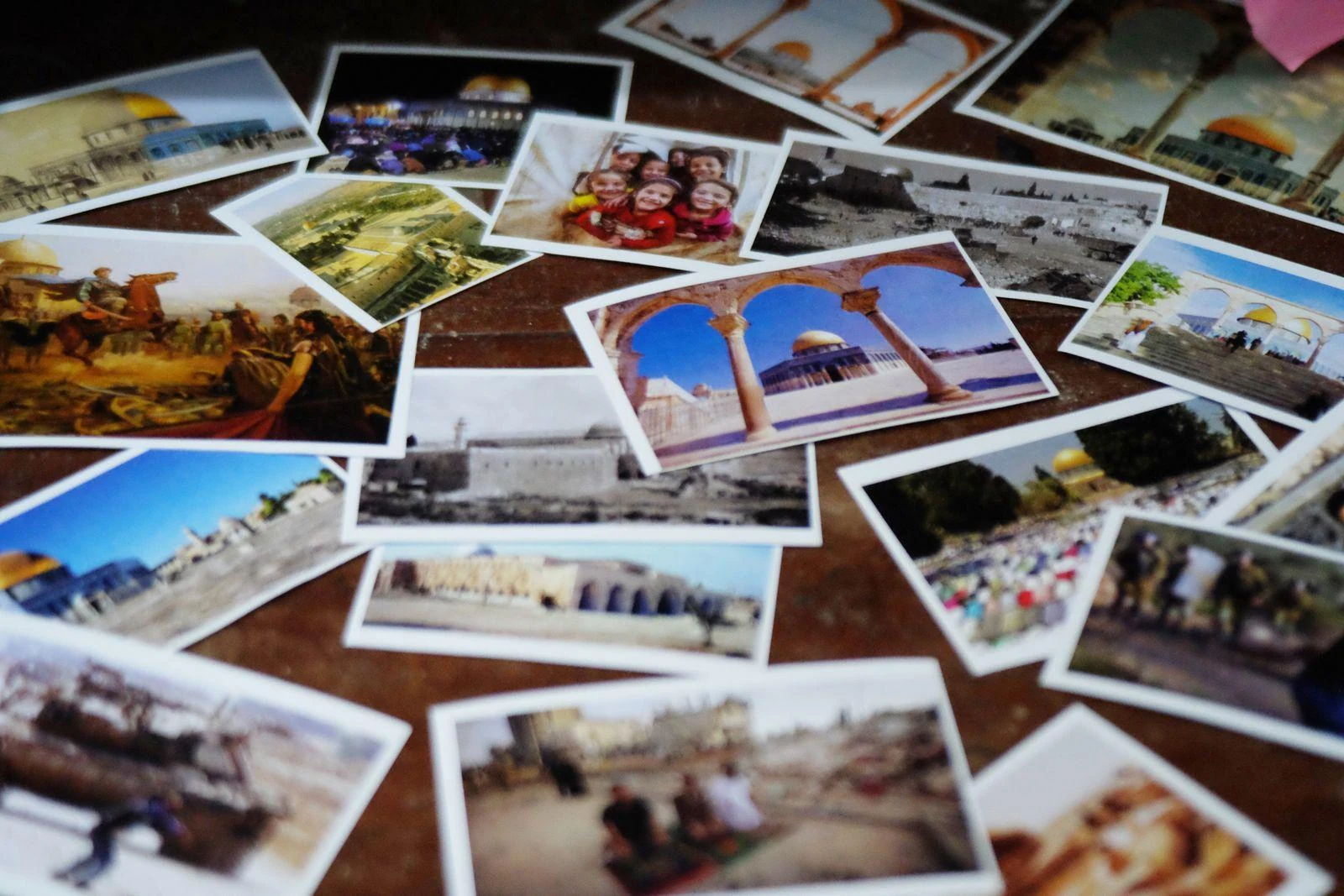 Printed travel photographs spread across a table for selection and comparison.
