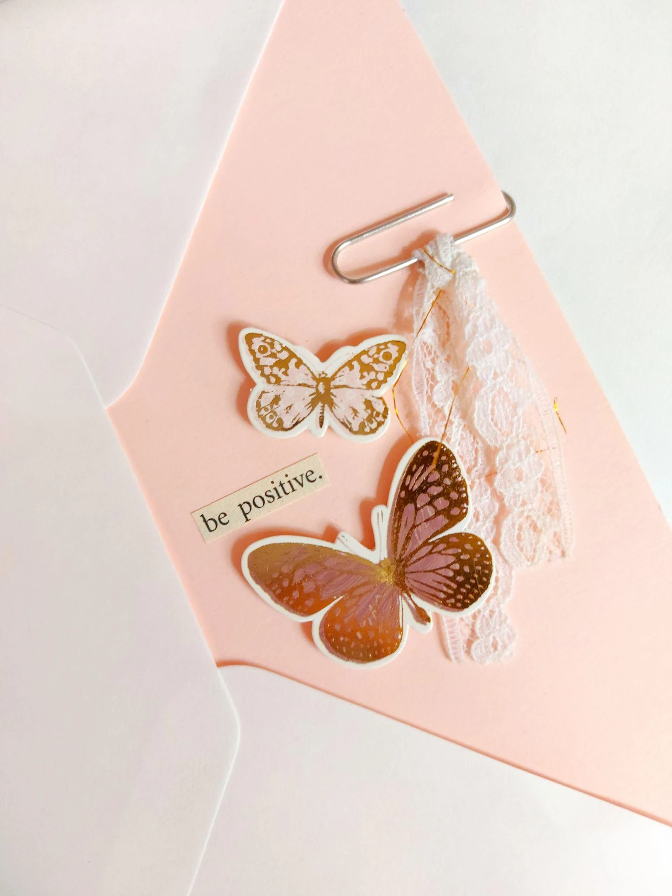 A decorated pink card with paper butterflies rests in an envelope, an example of art stationery.